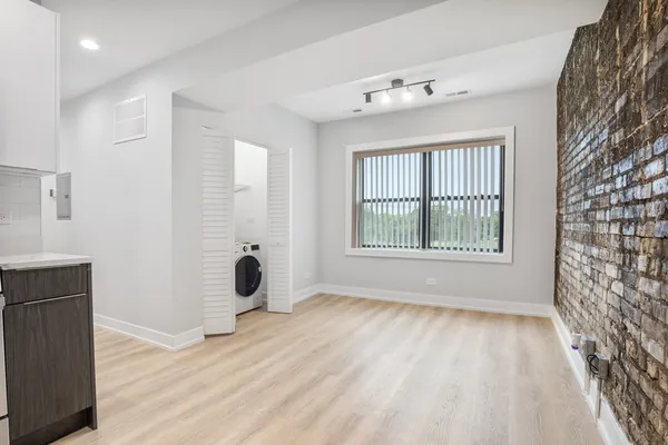 a view of an empty room with window and hardwood floor