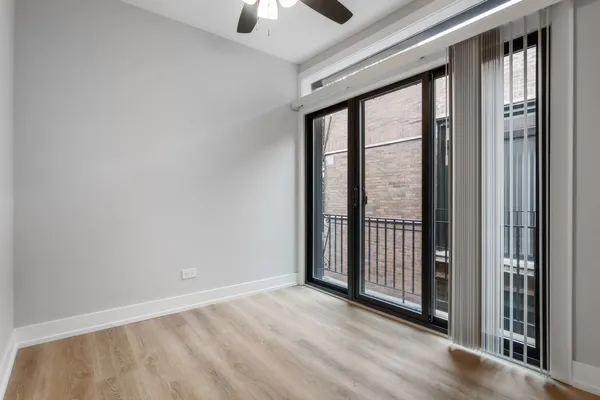 an empty room with ceiling fan and windows