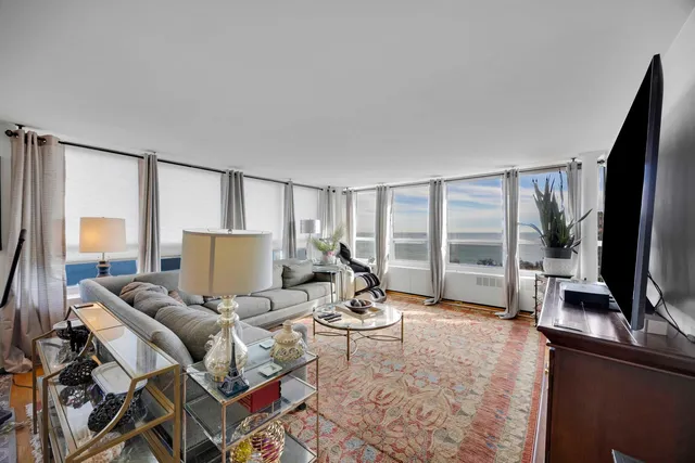 a living room with furniture a flat screen tv and a floor to ceiling window