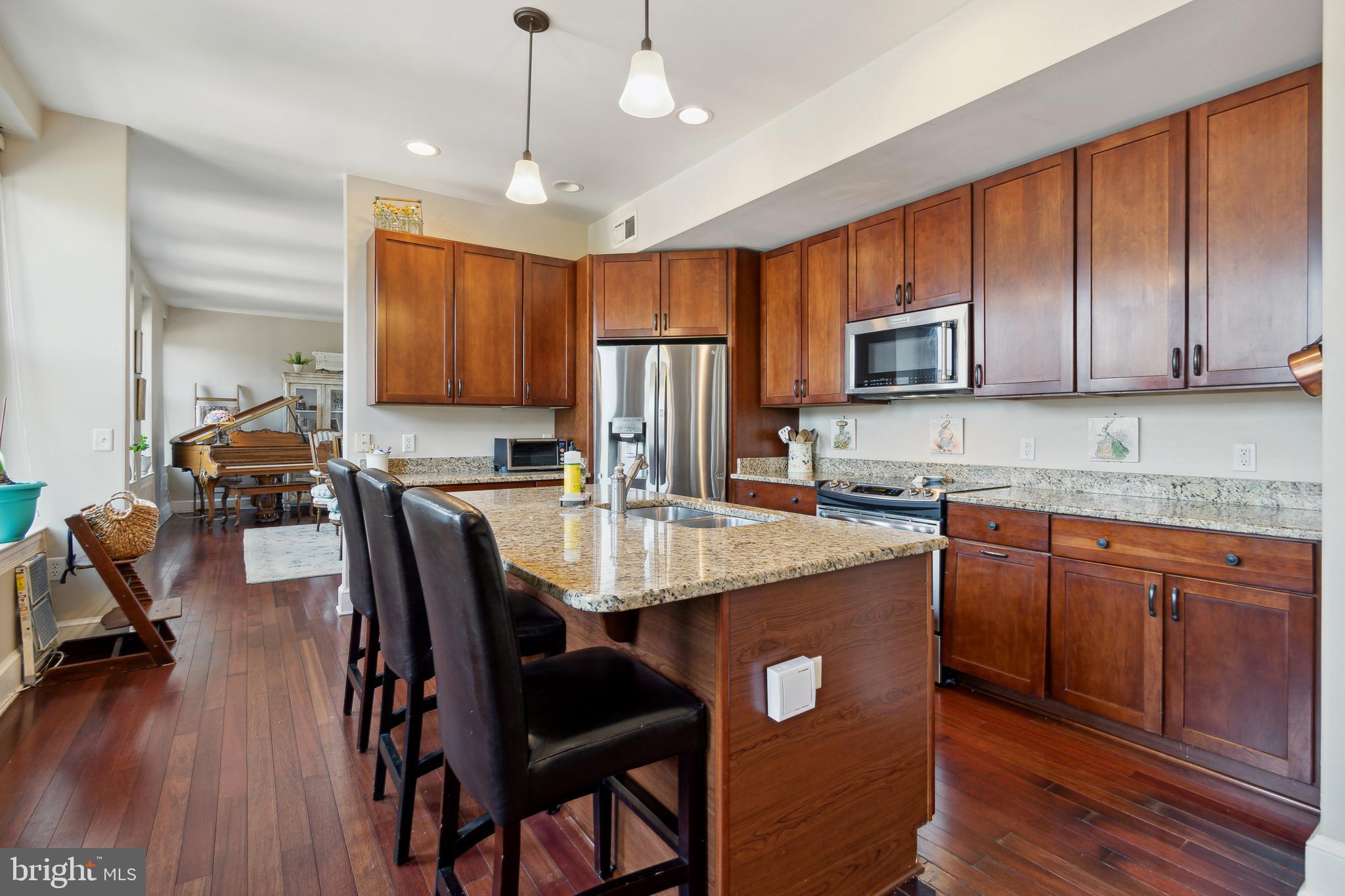 9610 Dewitt Drive, Unit B312 Silver Spring, MD 20910 - Photo 8 of 23 a kitchen with kitchen island granite countertop wooden cabinets and a refrigerator