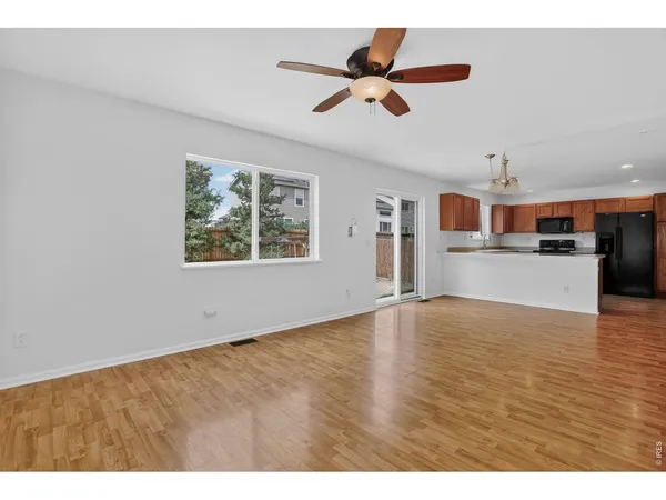 a view of kitchen and empty room with wooden floor