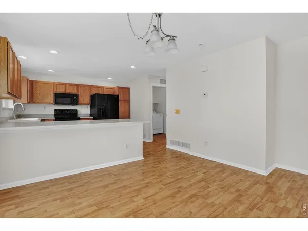 a kitchen with stainless steel appliances granite countertop a refrigerator a stove top oven a sink and dishwasher with wooden floor