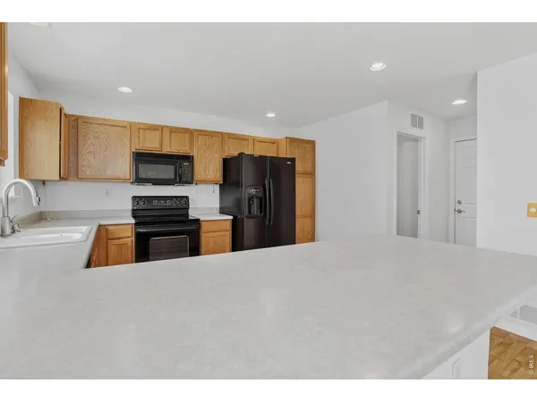 a kitchen with granite countertop wooden cabinets a sink a window and stainless steel appliances
