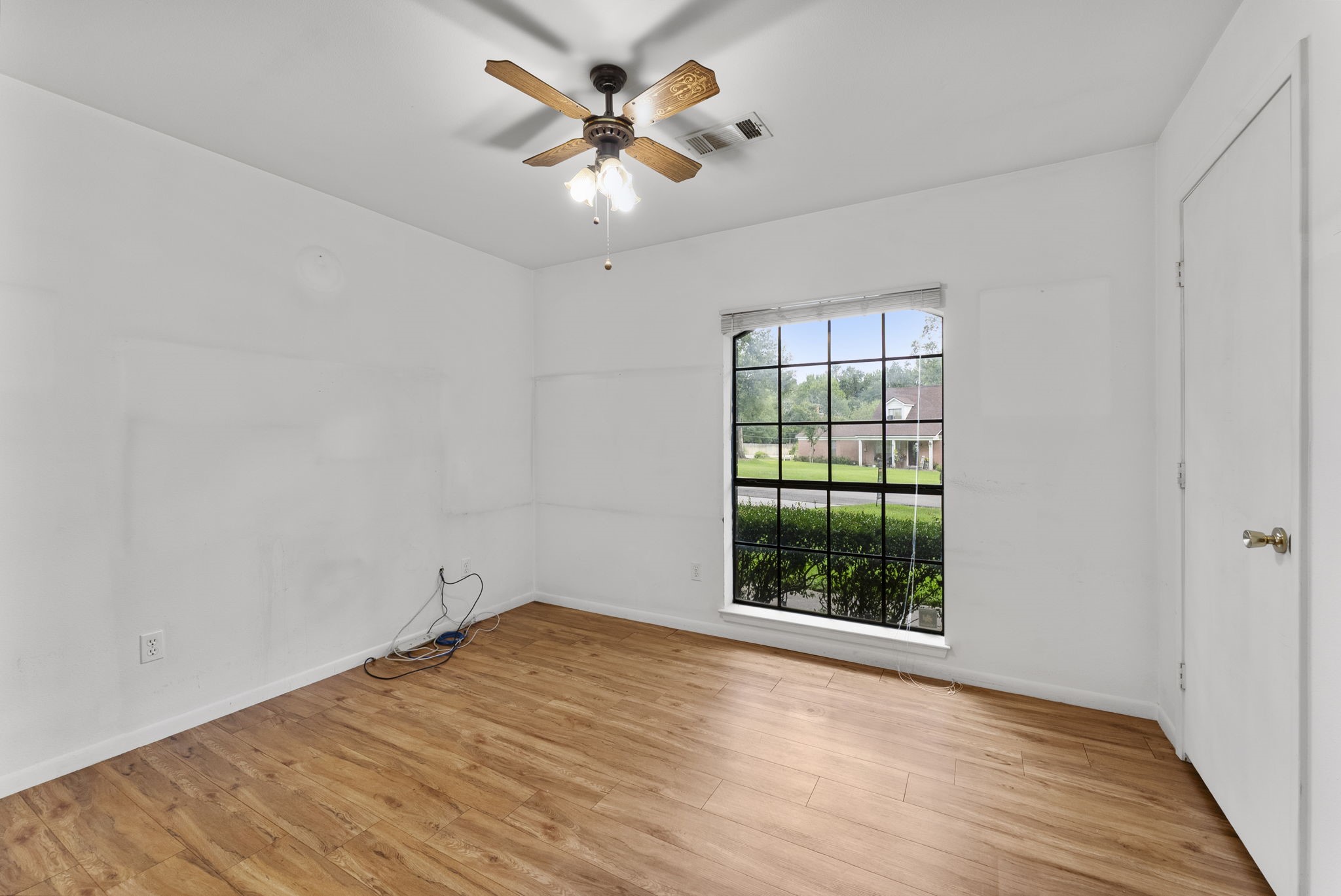 202 Sunset Boulevard Conroe, TX 77303 - Photo 28 of 50 This inviting guest bedroom features warm flooring, a large window with serene garden views, and a stylish ceiling fan, creating a cozy and welcoming retreat.