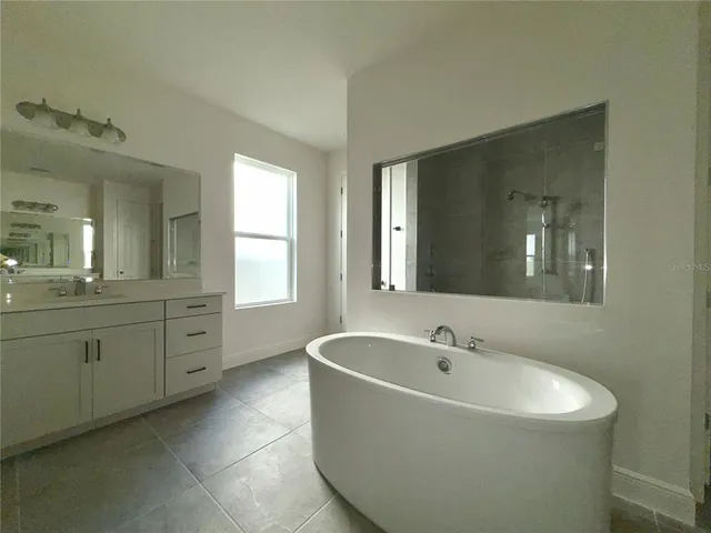 a spacious bathroom with a tub sink and mirror