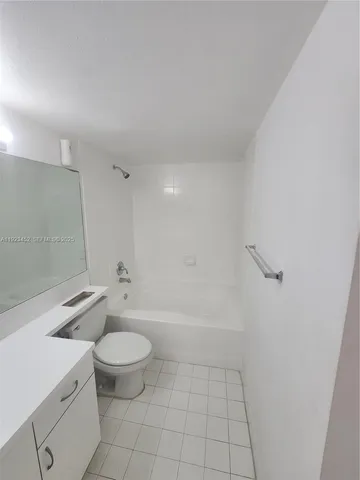 a bathroom with a granite countertop toilet a sink a mirror and a shower