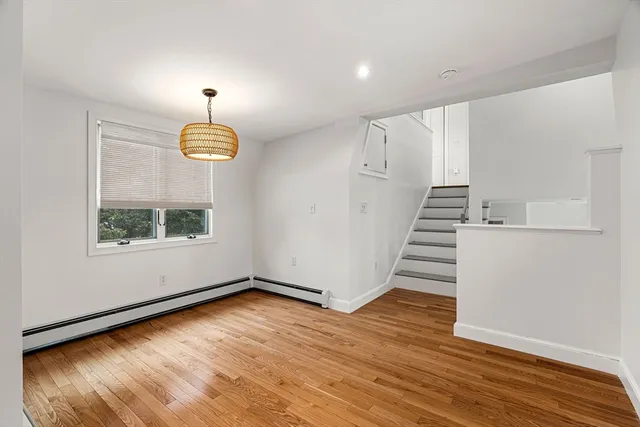 an empty room with wooden floor ceiling fan and windows