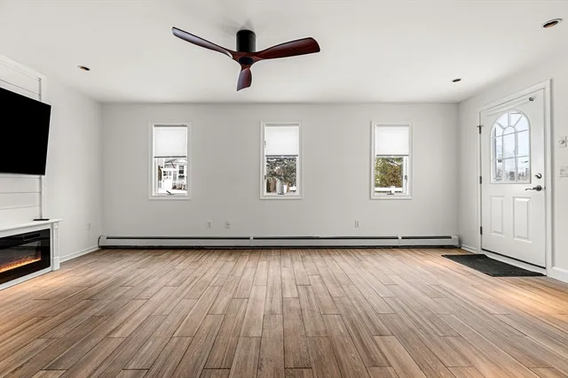 a view of an empty room with wooden floor stairs and a ceiling fan