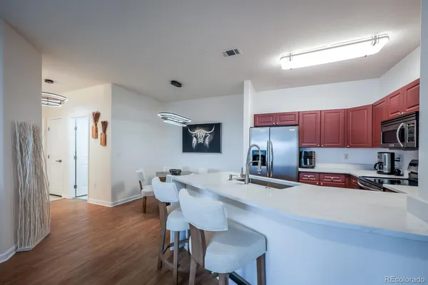 a kitchen with stainless steel appliances a sink a stove a refrigerator cabinets and wooden floor
