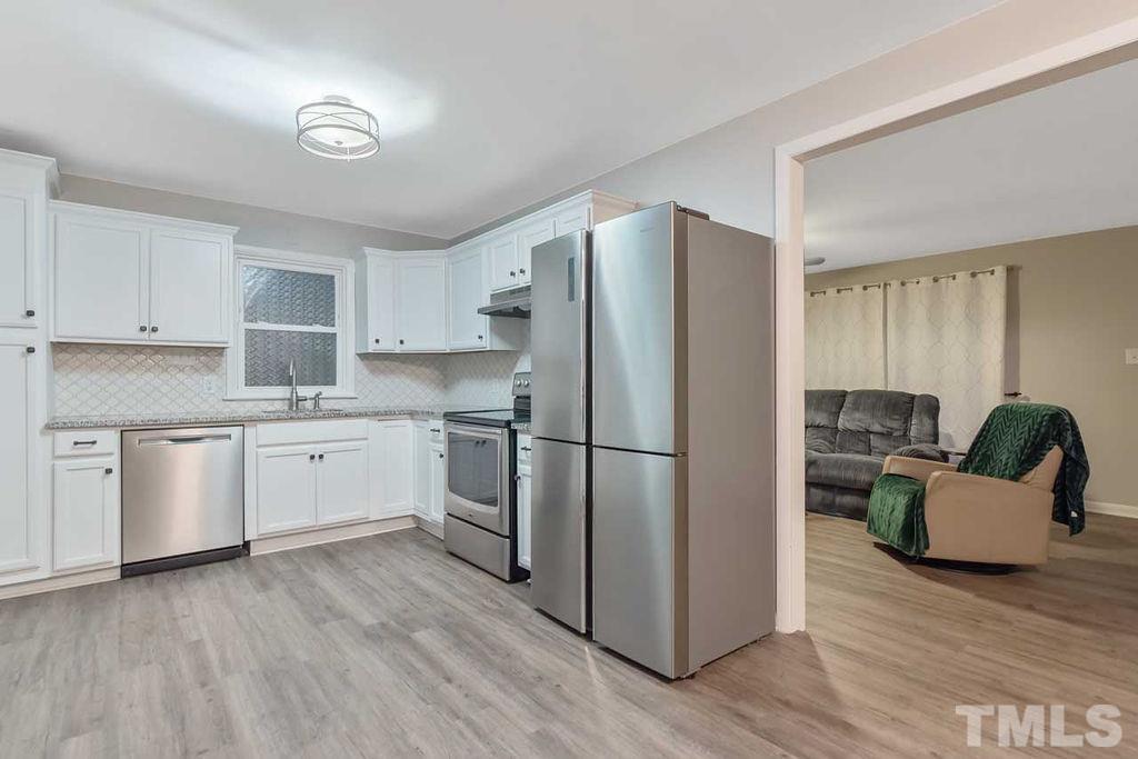 2613 Elmhurst Circle Raleigh, NC 27610 - Photo 16 of 29 a kitchen with a refrigerator a white cabinets and wooden floor