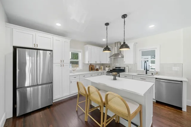 a kitchen with stainless steel appliances a dining table chairs stove and refrigerator