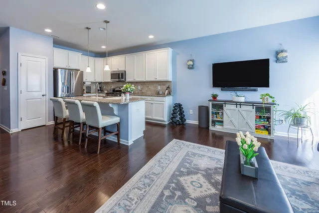a living room with stainless steel appliances furniture dining table and a flat screen tv