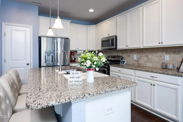 a kitchen with stainless steel appliances granite countertop a refrigerator a sink a white counter space and cabinets