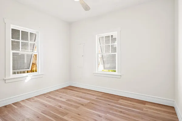 an empty room with wooden floor and windows
