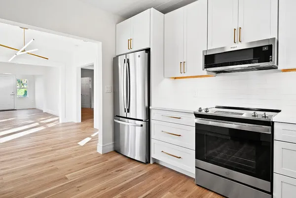 a kitchen with stainless steel appliances white cabinets white stove a refrigerator and a microwave