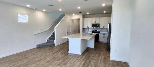 a large kitchen with stainless steel appliances a large counter top and stairs