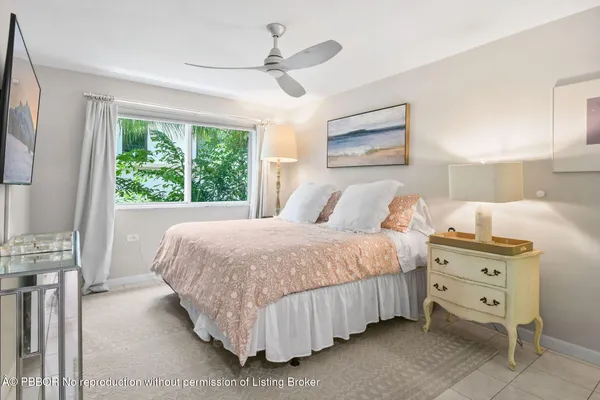 a bedroom with a bed next to a large window with a dresser