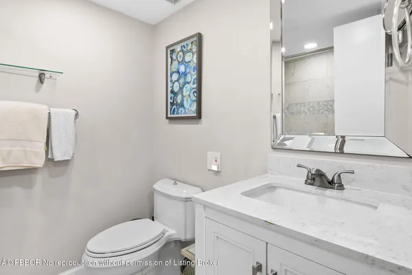 a bathroom with a granite countertop sink mirror vanity and toilet