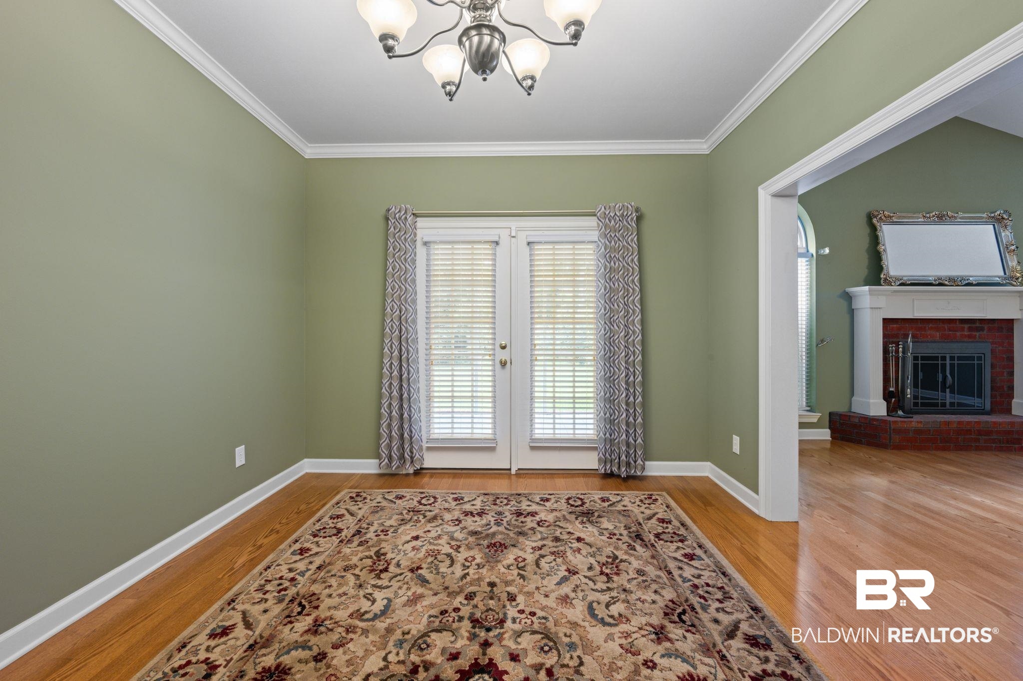 5618 Leytham Road Theodore, AL 36582 - Photo 17 of 60 Foyer entrance with ornamental molding, an inviting chandelier, wood-type flooring, and a brick fireplace