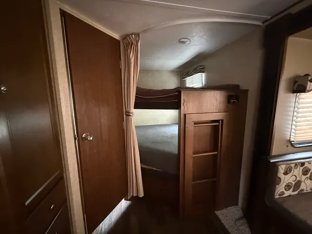 a view of a refrigerator in kitchen and an empty room in wooden floor