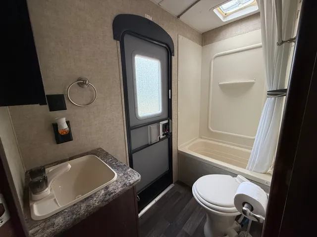 a bathroom with a granite countertop sink toilet and mirror
