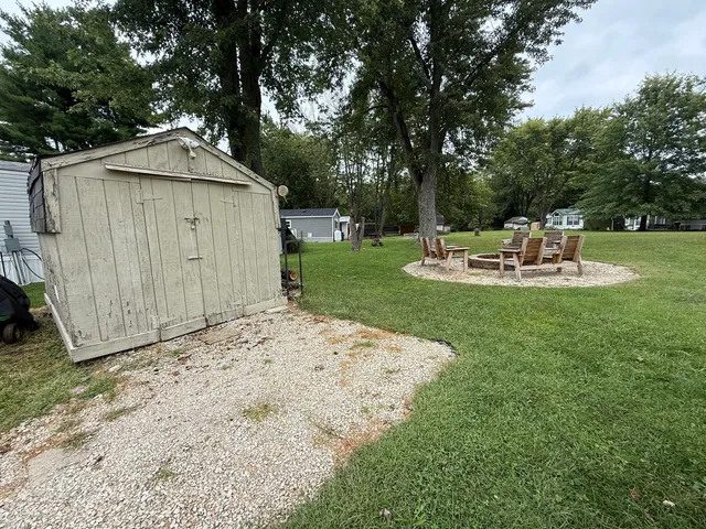 a backyard of a house with table and chairs plants and large tree
