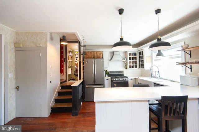 a kitchen with stainless steel appliances kitchen island granite countertop a refrigerator a stove and a sink with wooden floor