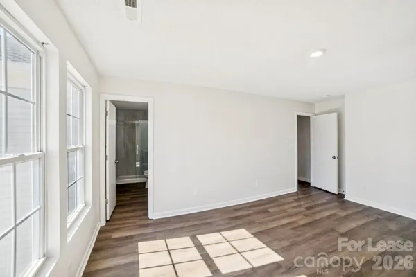 a view of a hallway with a bedroom and wooden floor
