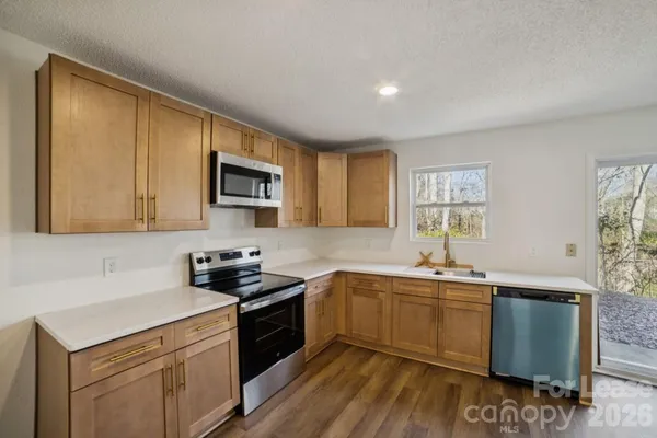a kitchen with stainless steel appliances granite countertop a sink a stove a refrigerator cabinets and a window