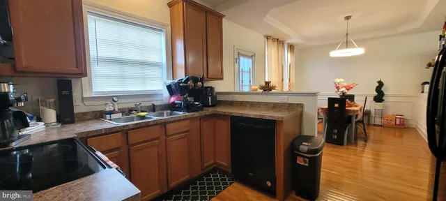 a kitchen with stainless steel appliances granite countertop a refrigerator a sink dishwasher a stove and a dining table with wooden floor