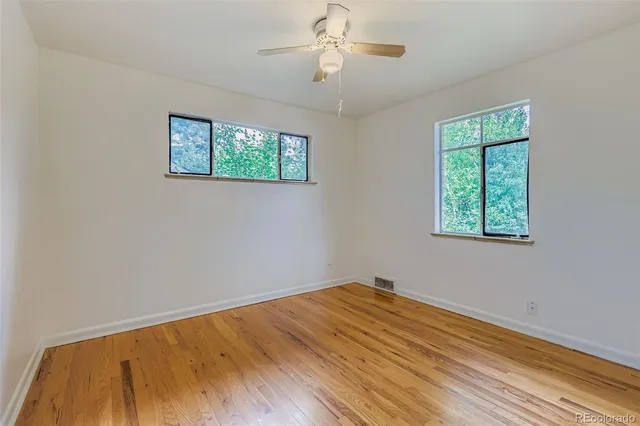a view of empty room with wooden floor and fan