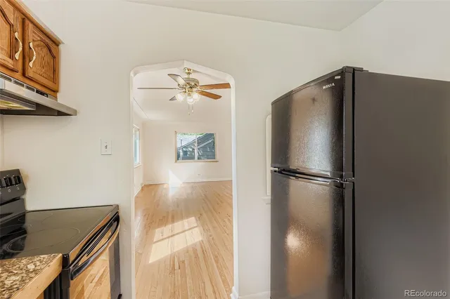 a view of a refrigerator in kitchen and an empty room