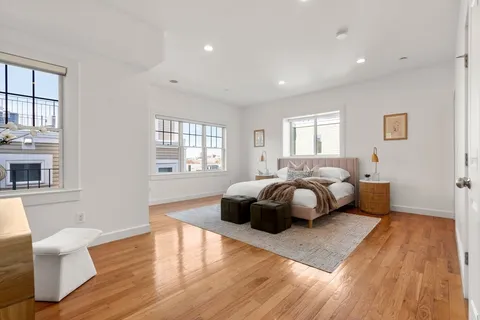 a spacious bedroom with a bed and wooden floor