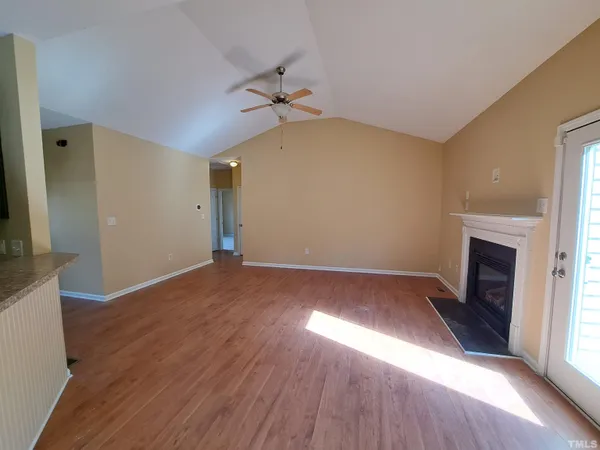 an empty room with wooden floor fireplace and windows