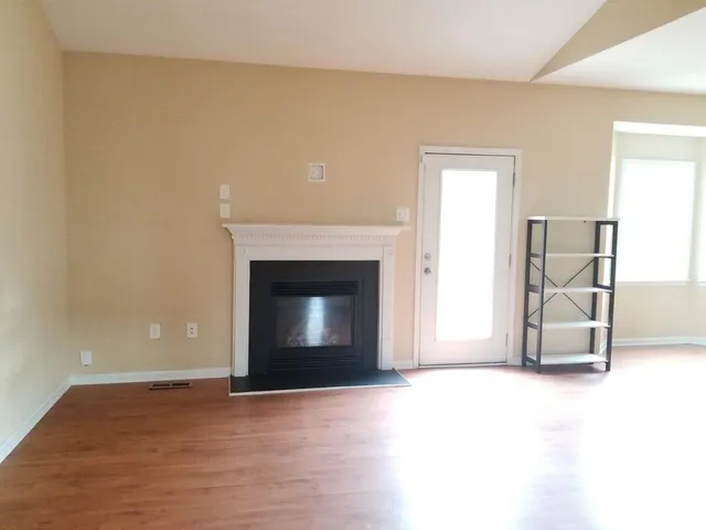 a view of empty room with wooden floor and fireplace