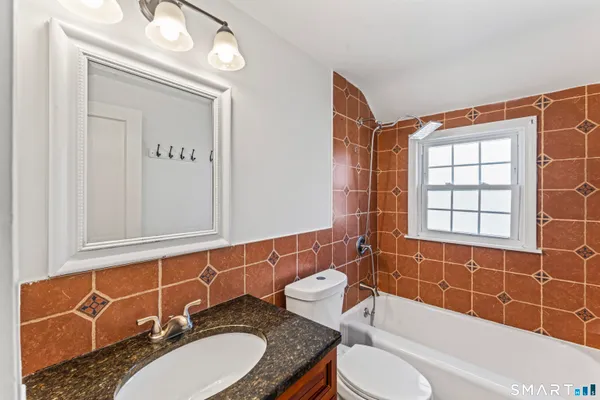 a bathroom with a granite countertop sink mirror toilet and bathtub