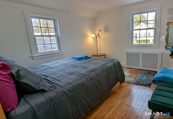 a bedroom with a bed window and wooden floor