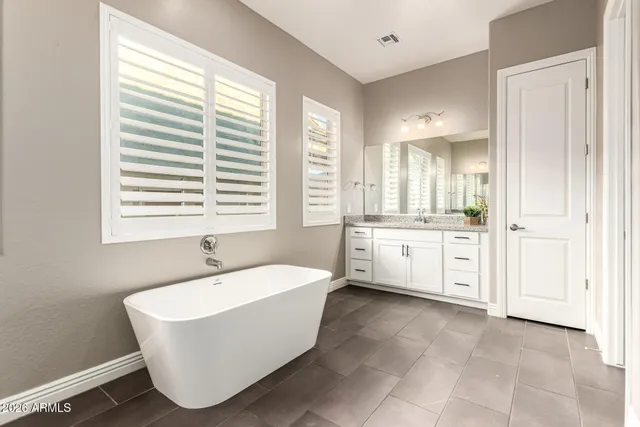 a spacious bathroom with a double vanity sink a mirror and a bathtub