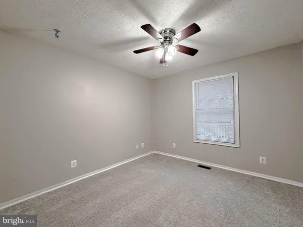 an empty room with chandelier fan and closet area