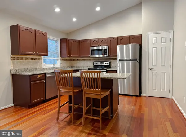 a kitchen with kitchen island granite countertop wooden cabinets stainless steel appliances and a counter space
