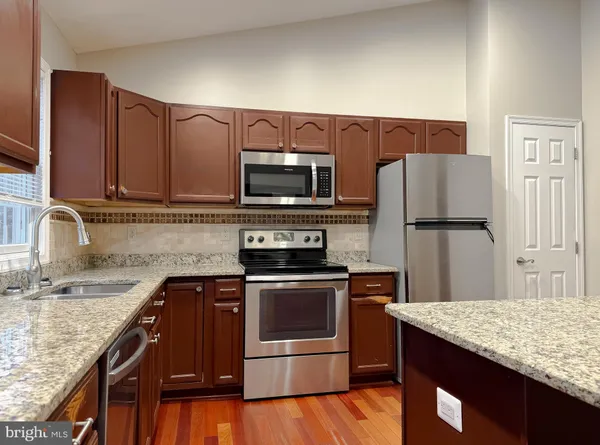 a kitchen with granite countertop a sink cabinets and stainless steel appliances