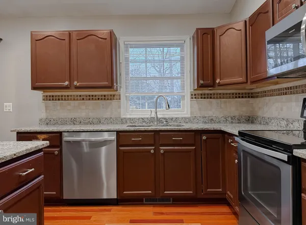 a kitchen with stainless steel appliances granite countertop a stove a sink dishwasher and a microwave oven with wooden floor