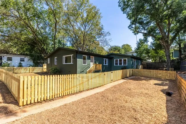 a view of a house with a wooden fence next to a yard