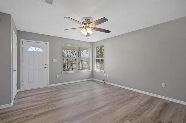 a view of an empty room with chandelier fan and wooden floor