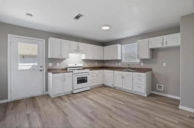 a kitchen with granite countertop white cabinets and white appliances