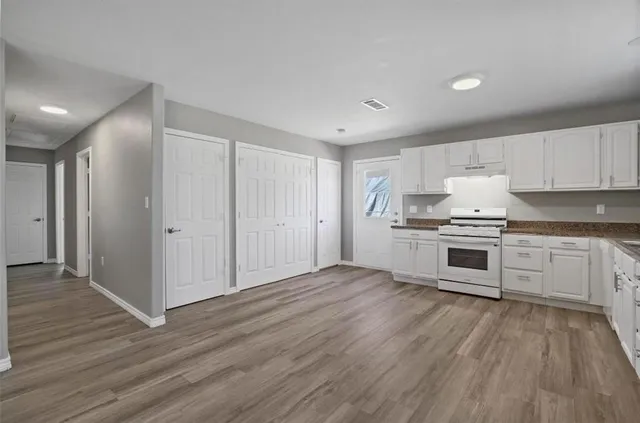 a kitchen with granite countertop white cabinets and stainless steel appliances