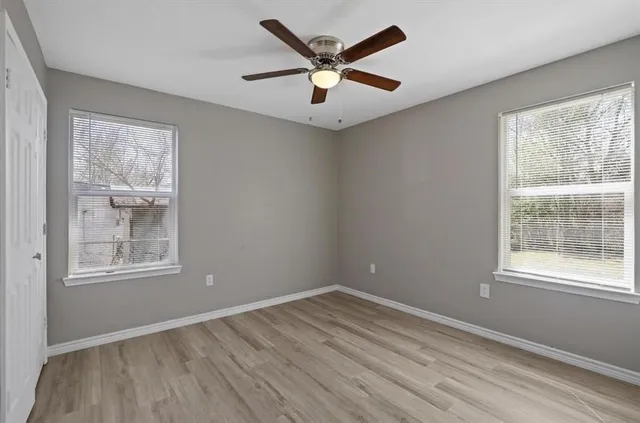 an empty room with wooden floor and windows