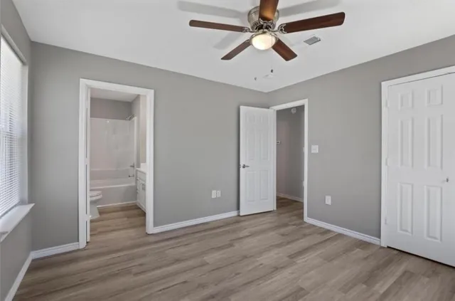 an empty room with wooden floor and ceiling fan
