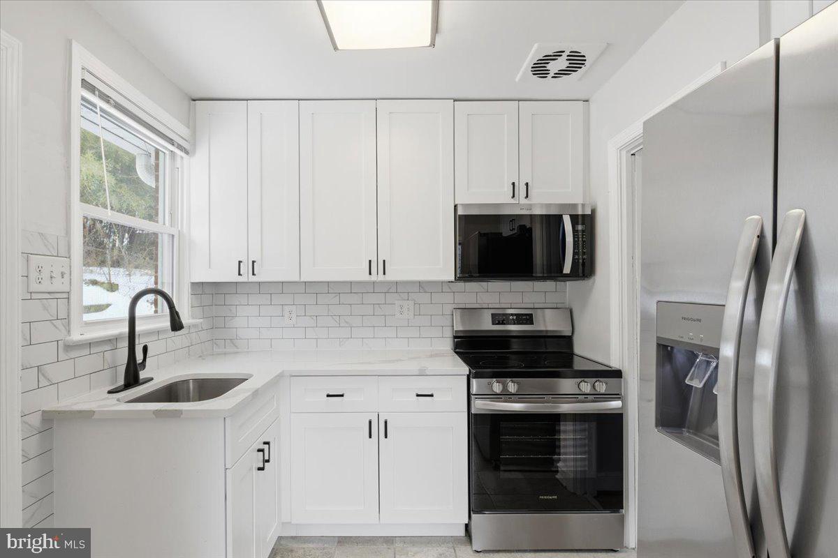 9704 Lorain Avenue Silver Spring, MD 20901 - Photo 7 of 26 a kitchen with stainless steel appliances a refrigerator sink and microwave