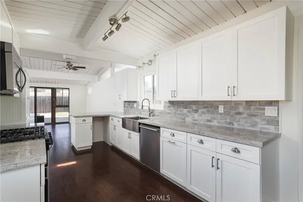 a kitchen with a sink dishwasher and white cabinets with wooden floor